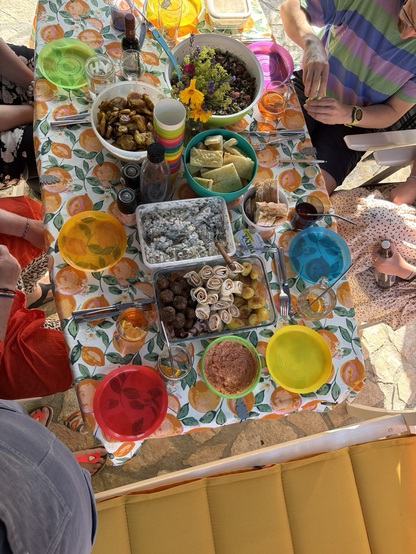 Ein Tisch von oben mit vielen verschiedenen Speisen und Tellern in bunten leuchtenden Farben.