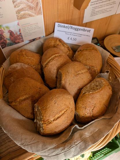 Ein Korb mit acht Brotlaiben und ein Schild: Dinkel/Roggenbrot 4,50€.