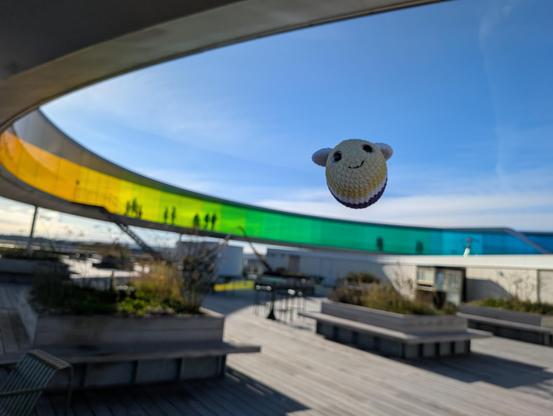 Gehäkelte Biene in der Luft vor dem Regenbogenrundgang am Dach des Museums. 