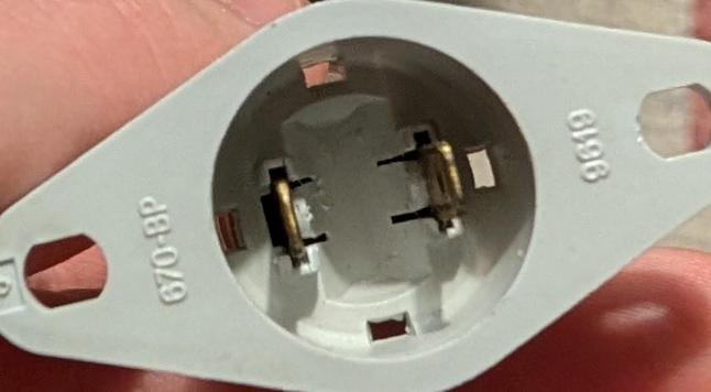 Unterseite des Sockels, wo man sieht, dass zwei Metallkontakte von der Lampe durch das Plastik gesteckt sind.

Beschriftung: 670-BP 9619