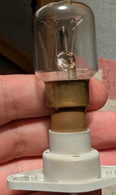 Eine kleine Glühbirne, etwa zwei Finger großer Glaszylinder, darunter ähnlich hoch Metall und dann ein Plastiksockel mit zwei Schraublöchern.