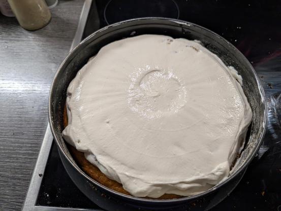 Kuchen mit einer weißen Creme aus Sahne und veganen Schmand bedeckt. 