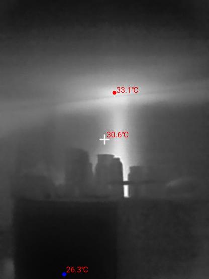 Black and white thermal image.  White area on the wall and the ceiling with a red indicator that the area is 33 °C. Blue indicator at the front of the fridge shows 26 °C.